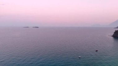 Yüksek irtifada çekilmiş, temiz güneş şemsiyeleri, berrak kıyı şeridi ve canlı turkuaz deniz içeren bir plajın yukarıdan aşağıya insansız hava aracı fotoğrafı.. 