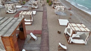 Yavaş yükselen insansız hava aracı görüntüsü, kabinler, şemsiyeler, su kaydırakları ve güzel sahil boyunca uzanan yatları olan lüks bir sahil beldesini ortaya çıkarıyor. 