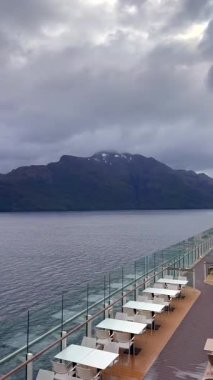 Sakin fiyort sularının ve ormanla kaplı adaların üzerindeki dramatik bulutlu gökyüzü Güney Patagonya 'da gezinen bir yolcu gemisinden görülüyor..