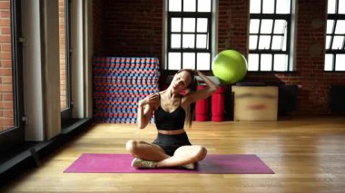 Beden eğitiminde yoga minderinde bacak bacak üstüne atmış genç bir kadın. 