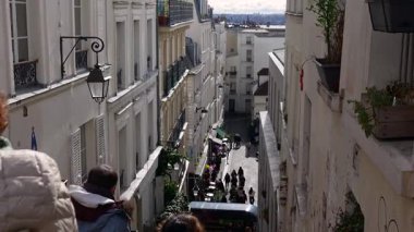 Paris, Fransa 04.01.2025 Montmartre merdivenlerinin tepesinden çekilen yüksek açılı çekim klasik Paris çatıları, balkonlar ve aşağıda hareketli parke taşlı bir sokak.