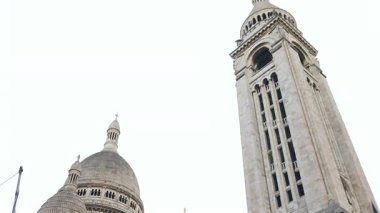Montmartre Paris 'teki Sacre Coeur Bazilikası' nın alçak açılı dikiz manzarası. Kubbeleri, kemerleri ve karmaşık tarihi taş işçiliği olan demir bir çitin arkasından görülüyor.. 