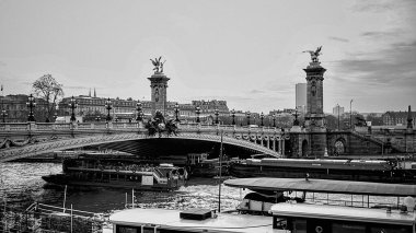 Paris 'teki Alexander Köprüsü' nün ebedi siyah-beyaz görüntüsü. Heykel detayları ve bulutlu gökyüzünün altında manzaralı nehir manzarası.. 