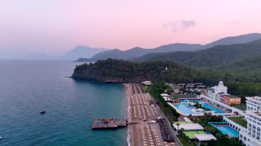 Güneşli yatakları, sonsuz havuzları, çam ormanı tepeleri ve gün doğumunda sakin turkuaz denizi olan lüks sahil manzaralı tepede.