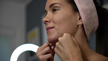 Cilt bakımı sırasında çene kemiğine parmak eklemleriyle masaj yapan yumuşak bir saç bandı takan ve yan bakışta doğal deri dokusu gösteren bir kadının yakın çekimi.