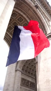 Paris 'teki Zafer Takı' nın altında dalgalanan Fransız üç renkli bayrağının yukarıdaki görüntüsü tarihi mimari ve ulusal gururu vurguluyor..