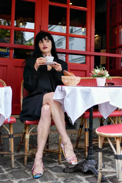 Paris 'te klasik bir kafede tek başına oturan şık bir kadın elinde bir fincan kahveyle yukarıya bakıyor, ayçöreği, çiçekleri ve kırmızı sandalyeleri ile rahat bir hava yaratıyor..