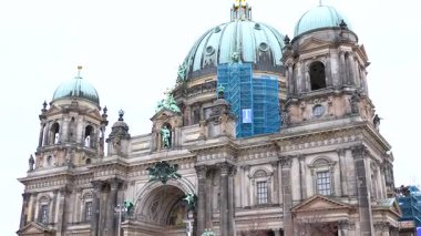 Berlin Katedrali 'nin ön cephesinde 17 Mayıs 2025' te yakalanan ve restorasyon sırasında kısmen mavi iskelelerle kaplanmış büyük kubbeler ve heykeller yer almaktadır.