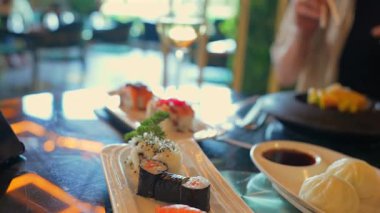 Lokantada soya ve şarapla servis edilen suşi ruloları ve buğulanmış çörekler. 