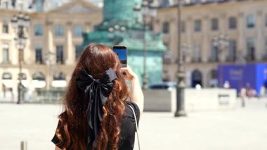 Paris 'teki Place Vendome' da elinde baget tutan bir kadın akıllı telefonuyla fotoğraf çekiyor.