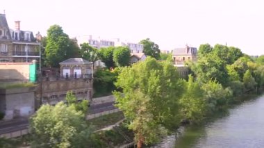 Nehir boyunca hareket eden tren manzaralı yeşil ağaçlar ve pencereden çekilen konut binaları