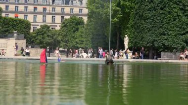26 Temmuz 2025 'te Tuileries Garden Paris' te dinlenen insanlarla gölde yüzen oyuncak botlar.