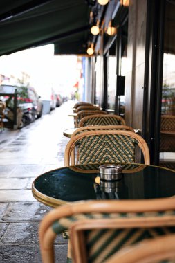 Paris Cafe 'nin boş açık hava koltukları klasik sandalyeler ve yuvarlak masalar 22 Şubat 2025' te ıslak, sessiz bir sokakta yakalandı..