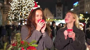 İki kadın festival sezonu boyunca Münih Almanya 'daki Noel pazarında sıcak içeceklerin tadını çıkarıyor. 5 Ocak 2025 'te yakalandı. 