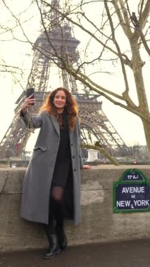 Güneşli bir günde Paris 'teki Eyfel Kulesi' nin yakınında selfie çeken gülümseyen kadın.