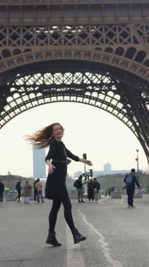 23 Nisan 2025 'te Paris' te Eyfel Kulesi 'nin altında yürüyen neşeli kadın.