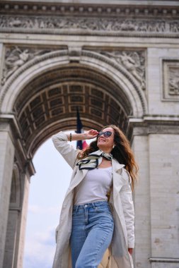 Paris Zafer Takı 'nın yanında duran trençkotlu genç kadın yaz günü Fransa' da kendinden emin ve şık görünüyor. 