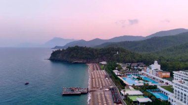 Gün batımında renkli otelleri olan deniz kıyısındaki bir tatil köyü.