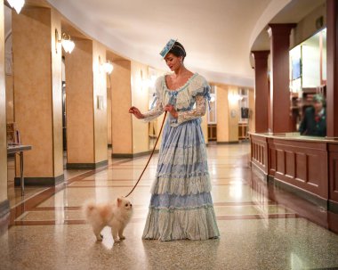 Lüks salonda beyaz pomeranya köpeğini gezdiren zarif bir kadın.