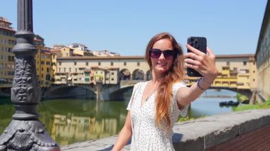 Ponte Vecchio Florence ile Arno Nehri kıyısında mutlu bir turist kadın.