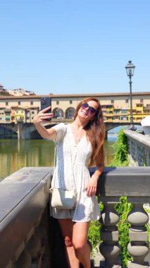 Floransa 'da Ponte Vecchio köprüsü yakınlarında selfie çeken genç bir kadın.