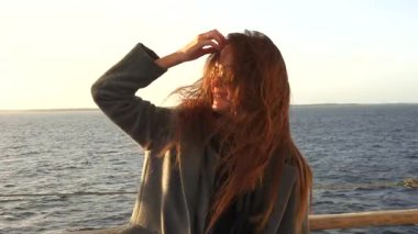 Feribot güvertesinde isimsiz bir kadın saçlarında rüzgarla ufka bakıyor. 