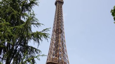 Yeşil ağaçlar ve yaz gökyüzü çerçeveli Eyfel Kulesi 
