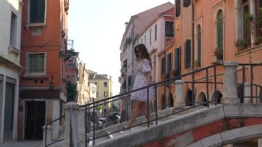 Renkli tarihi evler arasında Venedik köprüsünden geçen turistler