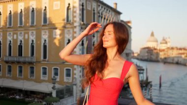 Gülümseyen kırmızı elbiseli kadın turist gün batımında Büyük Kanal İtalya 'da