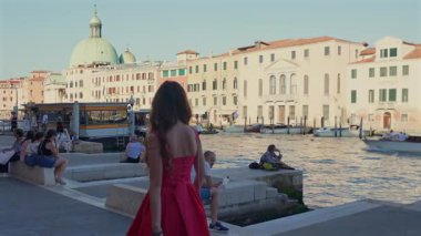 Büyük Kanal Venedik 'ten kırmızı elbiseli kadın. İtalya 29 Haziran 2025 yazı işleri.