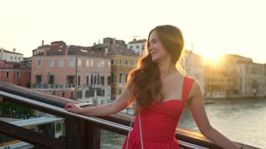 Gülümseyen kırmızı elbiseli kadın köprü kenarında duruyor Venedik 'i tırabzanla geçiyor