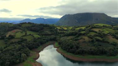 Çiftlik arazilerinin panoramik manzarası ve bulutlu dağ zirvesi