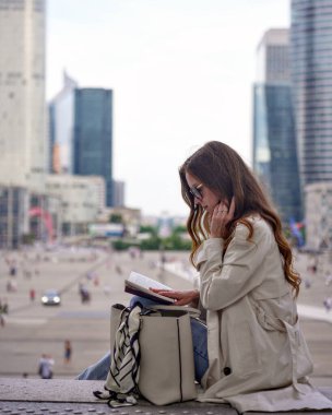 Akıllı telefon ve defterle birden fazla iş yapan genç bir kadın.