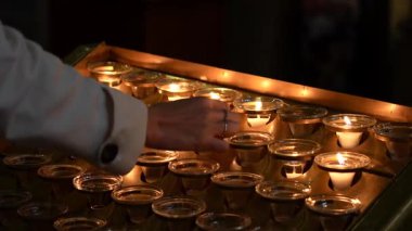Paris Katedrali 'ndeki dua mumlarının arasına mum koyan kadına yakın çekim. 