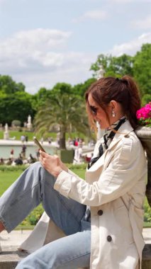 Lüksemburg Bahçeleri 'nde Paris Fransa' da açık havada telefonuyla oturan rahat bir kadın. 