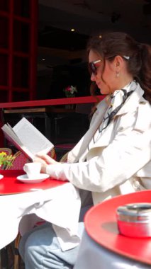 Paris Kafe Terasında kahve içip kitap okuyan zarif bir kadın. 