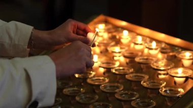 Paris kilisesinde mum tutan ve yakan bir kadın. 