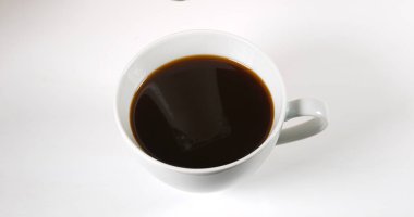 Beyaz arkaplana karşı bir fincanda kahve dolduruluyor