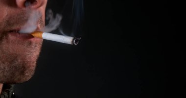 Siyah arka planda sigara içen bir adam