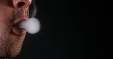 Siyah arka planda sigara içen bir adam