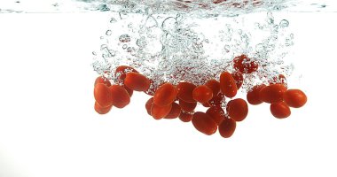 Kirazlı domatesler, solanyum likopersicum, beyaz arka planda suya düşen meyveler.