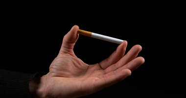 Siyah arka planda sigara kıran adamın eli.