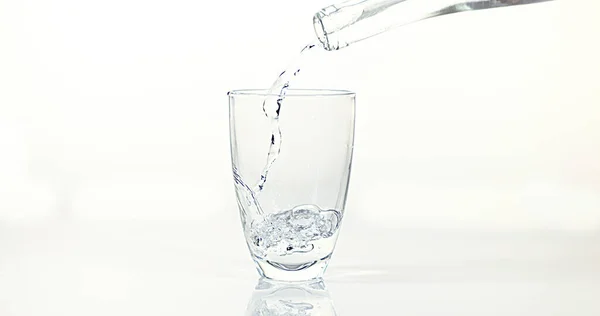 白を背景にガラスに水を注ぐ — ストック写真