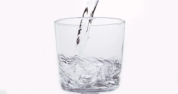 白を背景にガラスに水を注ぐ — ストック写真