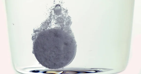 ホワイトバックグラウンドに対する水のガラスに落ちて溶解する錠剤 — ストック写真