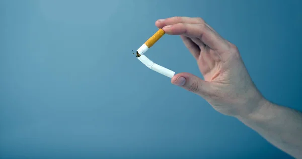 Hand Breken Van Een Sigaret Tegen Een Blauwe Achtergrond — Stockfoto