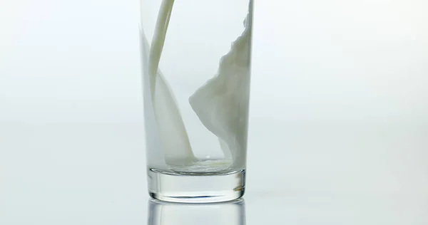 Beyaz Arkaplan Karşı Bardağa Süt Dökülüyor — Stok fotoğraf
