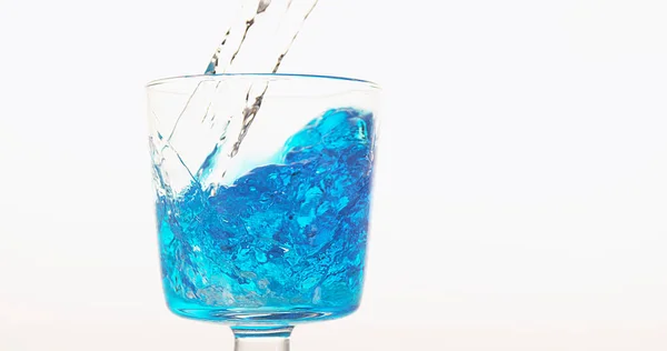 Água Sendo Derramada Vidro Contra Fundo Branco Azul Parte Inferior — Fotografia de Stock