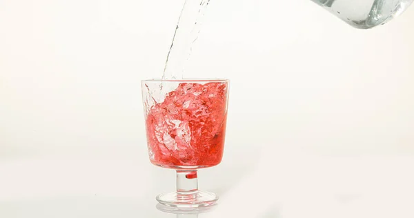 Water Wordt Gegoten Glas Tegen Witte Achtergrond Rood Bodem Van — Stockfoto