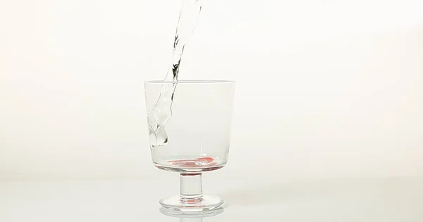 Water Being Poured Glass White Background Red Bottom Glass — Stock Photo, Image